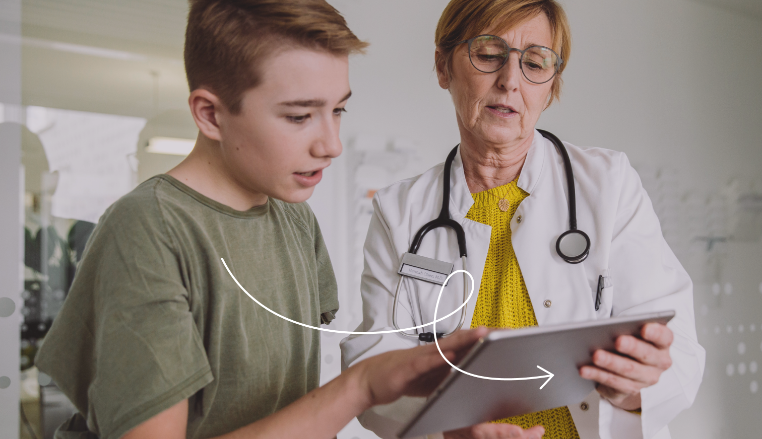 Médecin généraliste montrant une tablette à un adolescent garçon.
